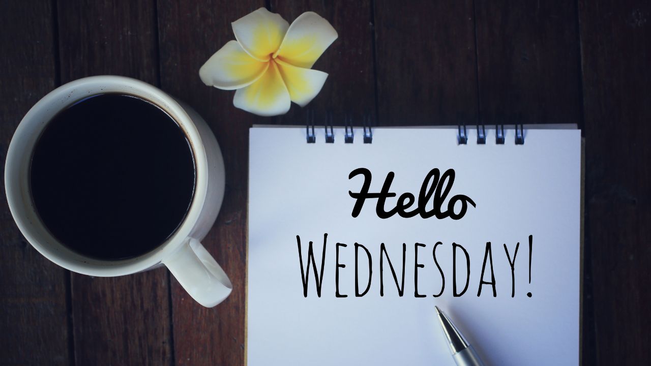 A cup of coffee beside a notepad with "Wednesday Morning Prayer" written on it, a pen, and a frangipani flower, all set on a wooden surface.