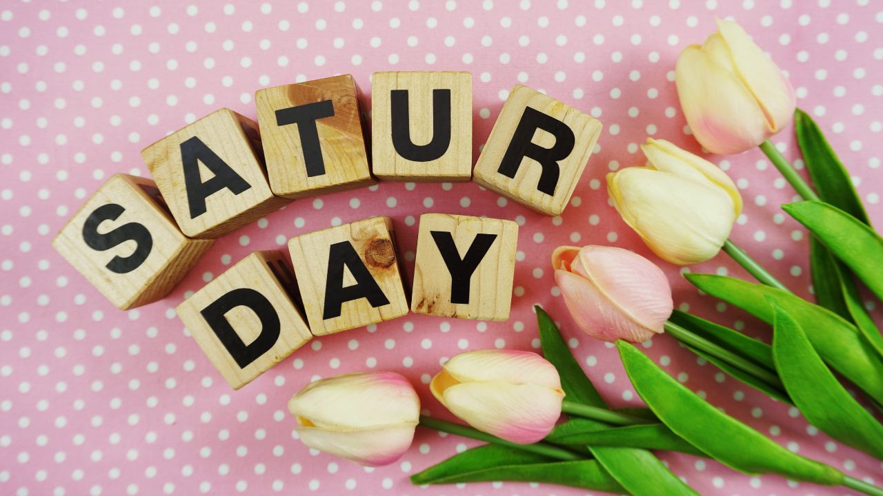 Wooden blocks spelling "Saturday Morning Prayer" on a pink polka dot background, with pale pink tulips arranged to the side.