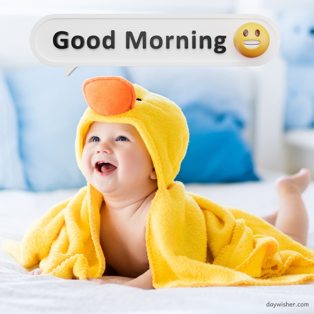 Joyful baby in a yellow duck towel smiling brightly on a bed, with a "Good Morning" speech bubble above, perfect for sharing as good morning baby images to spread cheer and warmth.