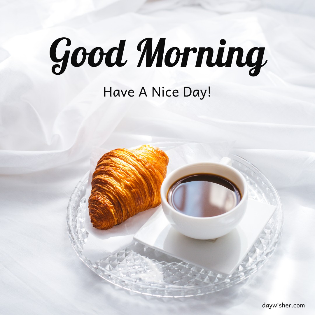 Elegant breakfast setting with a croissant and a cup of coffee on a crystal-clear plate, set against a backdrop of white linens, accompanied by a 'Good Morning, Have A Nice Day!' message.