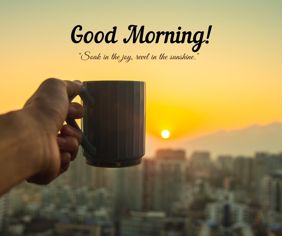 A hand holding a mug against the backdrop of a city skyline at sunrise. The sun is rising over the buildings, casting a warm, golden light. The text "Good Morning!" is written above, with the quote "Soak in the joy, revel in the sunshine." This image captures the essence of a beautiful good morning with natural sunshine and an inspiring quote, perfect for sharing positive vibes.