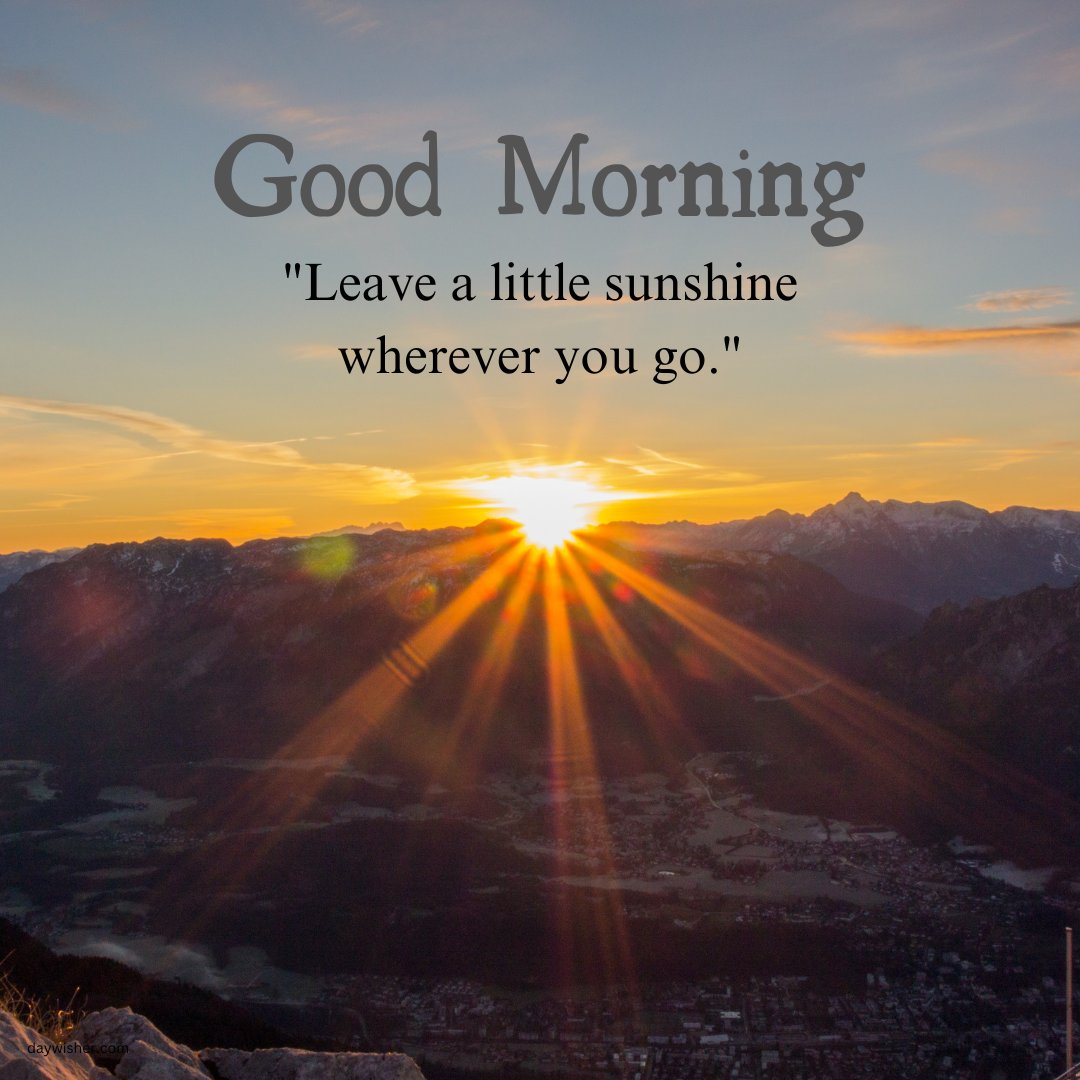 A breathtaking sunrise over a mountain range, with the sun's rays spreading across the sky and landscape. The image includes the text "Good Morning" and the quote "Leave a little sunshine wherever you go." This scene captures the natural beauty of a new day, making it a perfect good morning sunshine image with a motivational message.